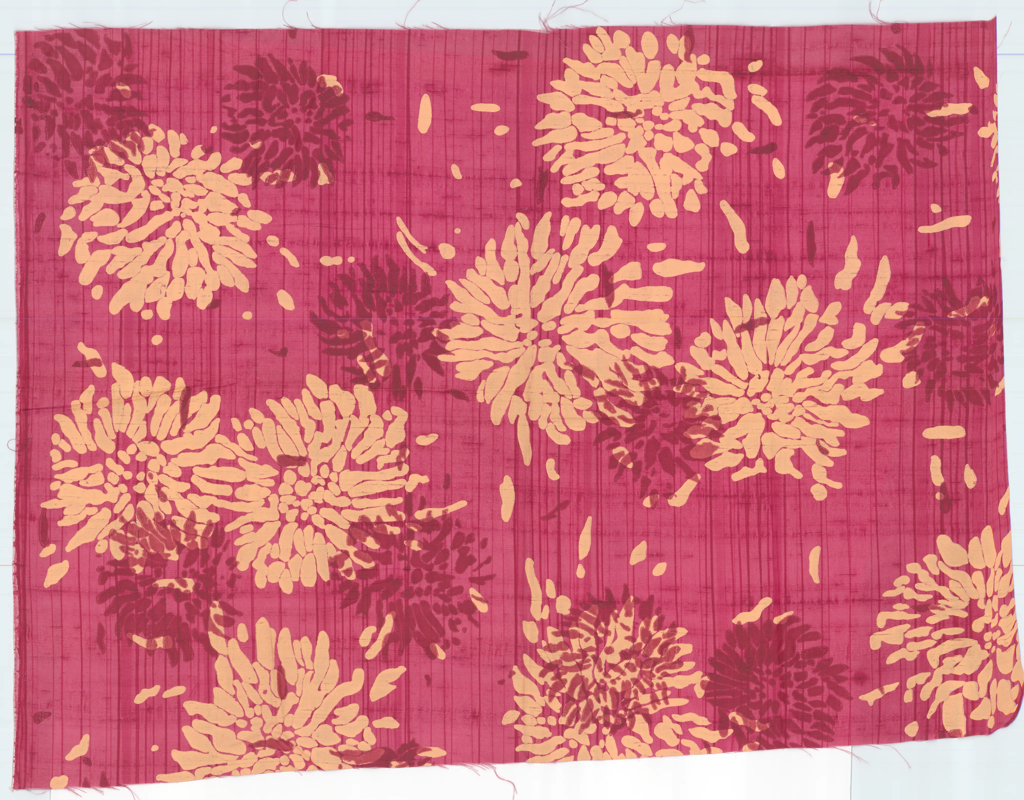 A close-up detail of a textured pinkish-red fabric patterned with abstract, jagged-edged floral shapes in peach and dark burgundy.